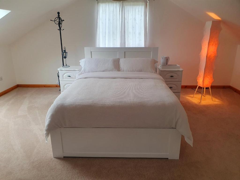 um quarto branco com uma cama branca e uma janela em Urkers' Guest Accommodation em Crossmaglen