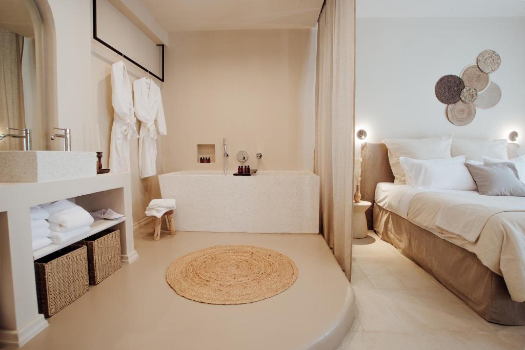 Dormitorio blanco con bañera, cama y lavamanos en Thymises Boutique Hotel en Kakopetria