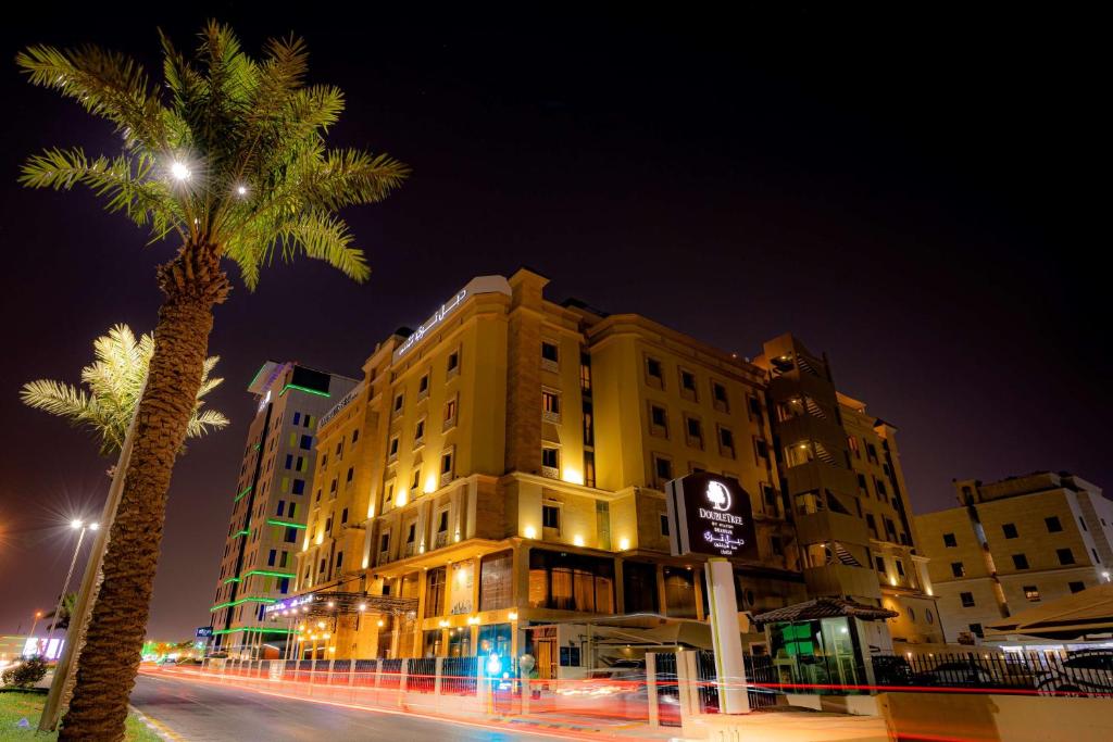 a building with a palm tree in front of a street at DoubleTree by Hilton Dhahran in Al Khobar