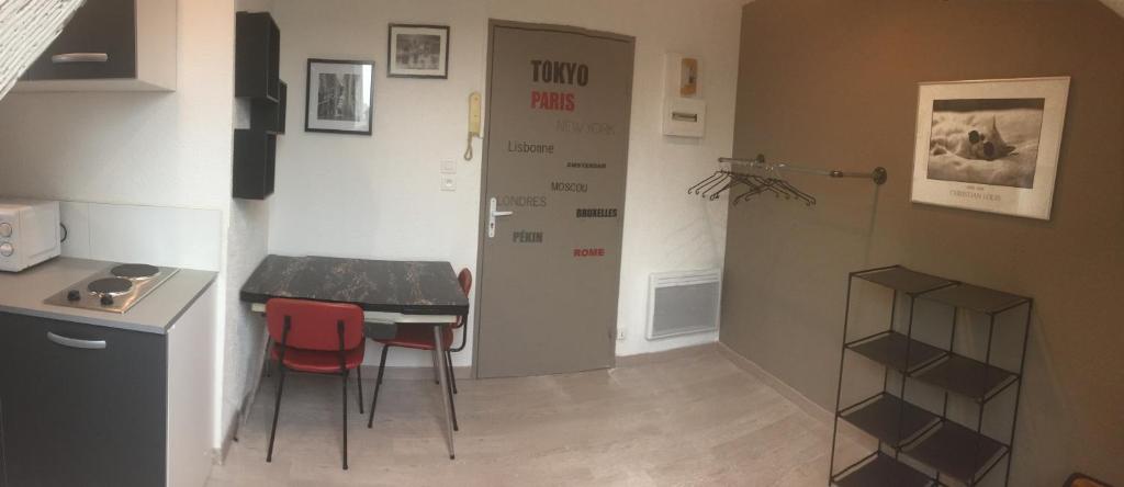 a small kitchen with a table and two red chairs at Studio moderne, étage 3, avec literie de qualité prémium in Belfort
