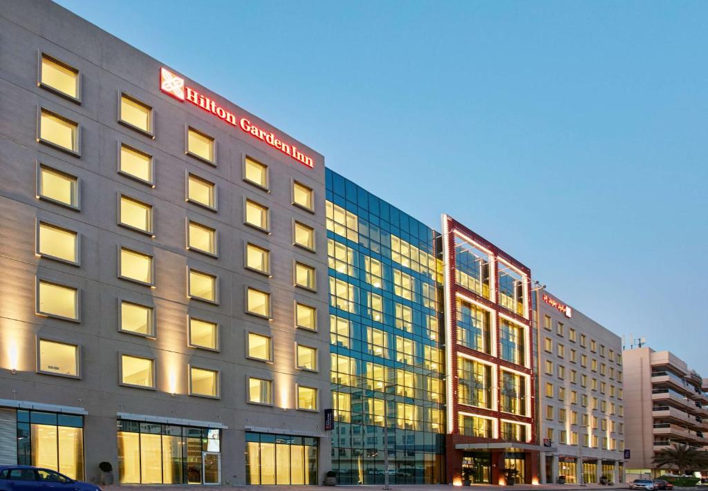 Hilton Garden Inn Dubai, Mall Avenue في دبي: مبنى كبير مع العديد من النوافذ على شارع