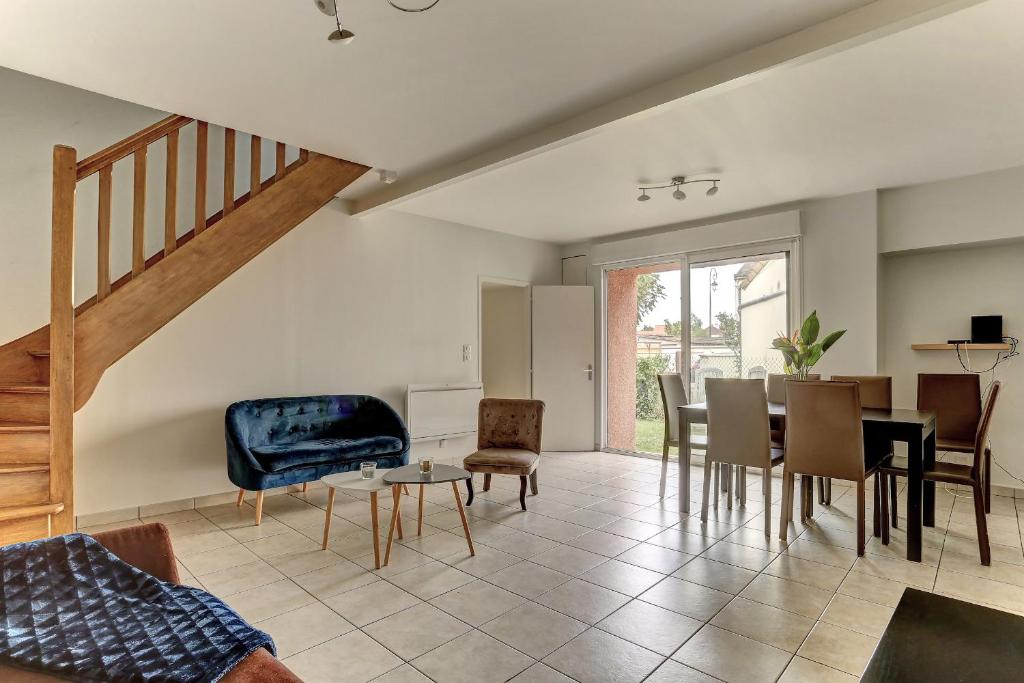 uma sala de estar com uma escada e uma mesa e cadeiras em Le Manet- Montigny em Montigny-le-Bretonneux