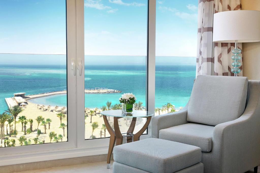 a living room with a chair and a view of the ocean at Hilton Hurghada Plaza Hotel in Hurghada