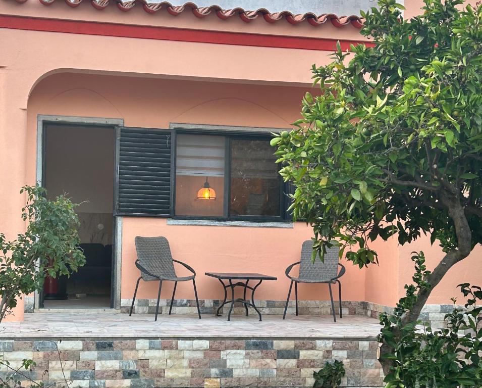 dos sillas y una mesa frente a un edificio en Apartamento Ritmo do Mar, en Quatrim do Sul