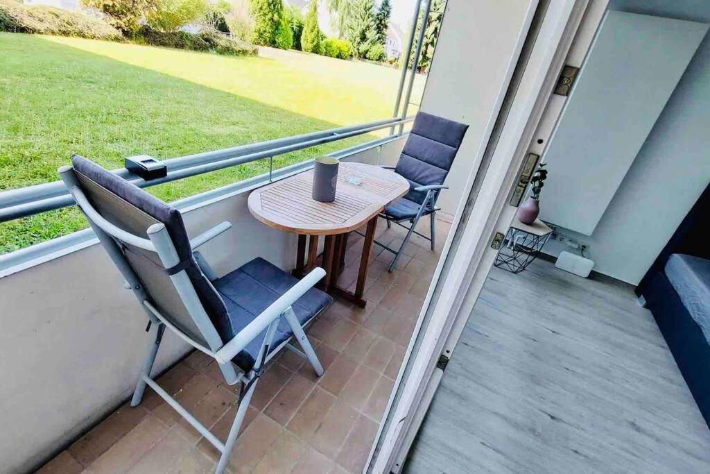 a patio with a table and chairs on a balcony at Flat - WiFi + SmartTV + Balcony in Sankt Augustin