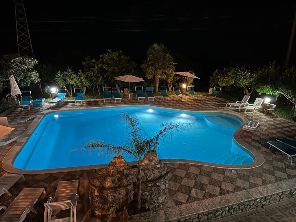 a swimming pool at night with chairs and umbrellas at Hotel Royal in Coccorino