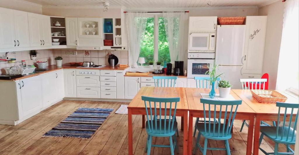 a kitchen with a wooden table and blue chairs at Berggården Vandrarhem in Gnarp