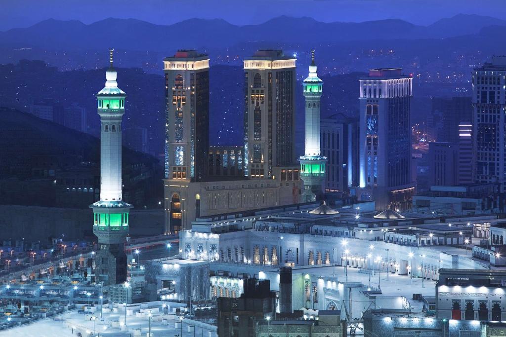 uma cidade iluminada à noite com os seus edifícios em Hilton Makkah Convention Hotel em Meca