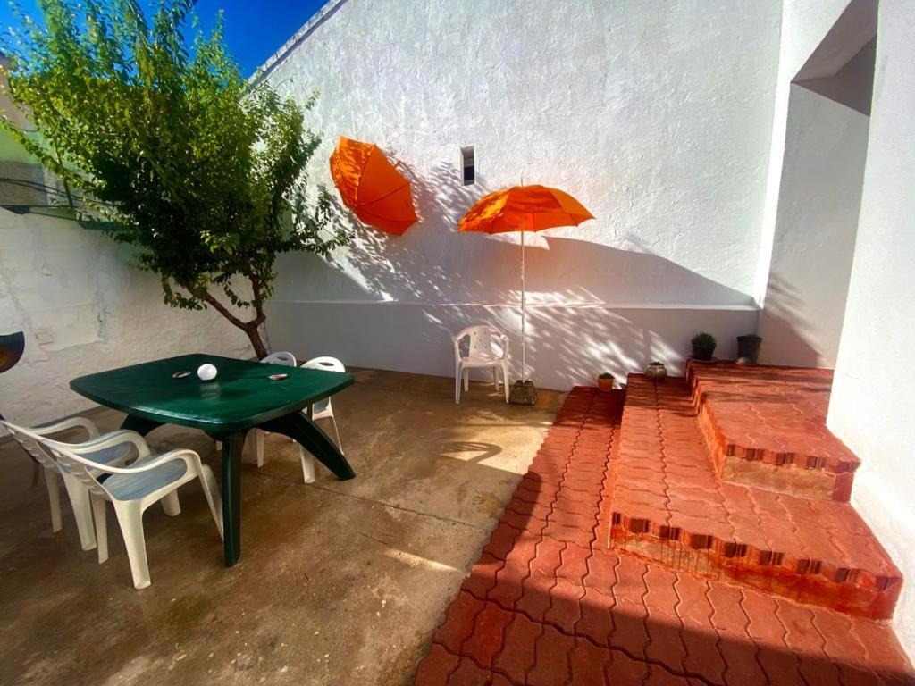 eine Terrasse mit einem grünen Tisch, Stühlen und Sonnenschirmen in der Unterkunft Casa agradable el Cañavate in El Cañavate