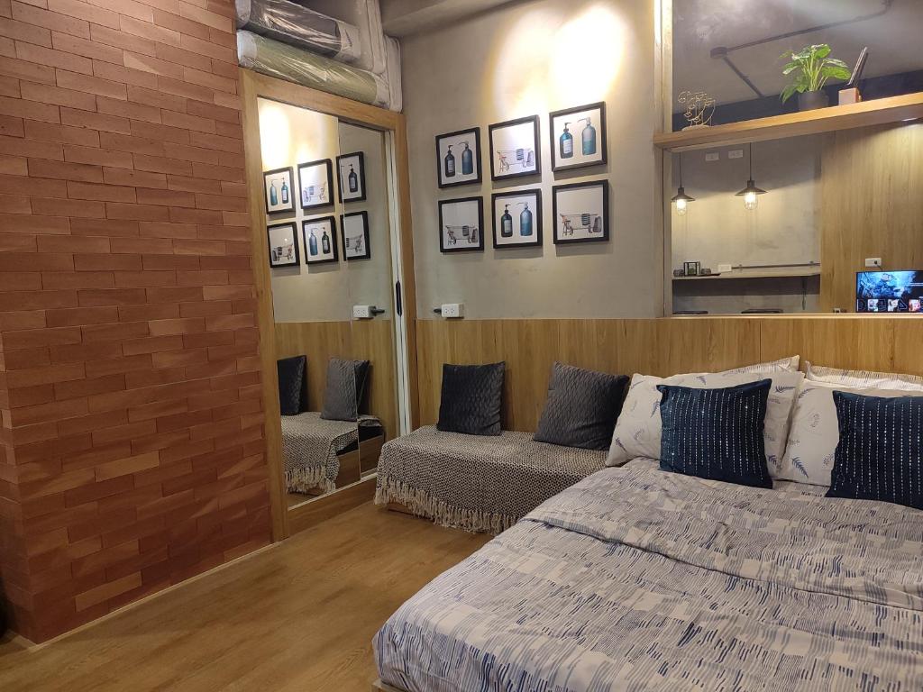 a bedroom with a bed and a couch and a mirror at The Zen Suites at Mesatierra Garden Residences in Davao City