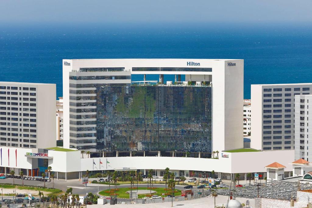 a large white building in front of the ocean at Hilton Tanger City Center Hotel & Residences in Tangier