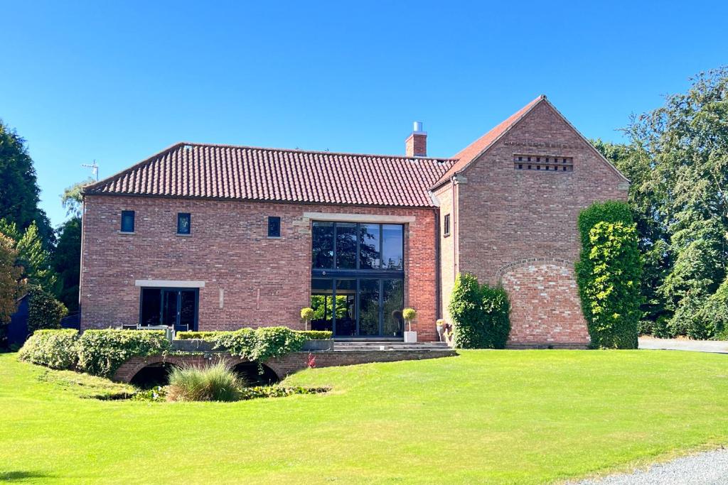 a large brick house with a grass yard at One Park Lane in Southwell