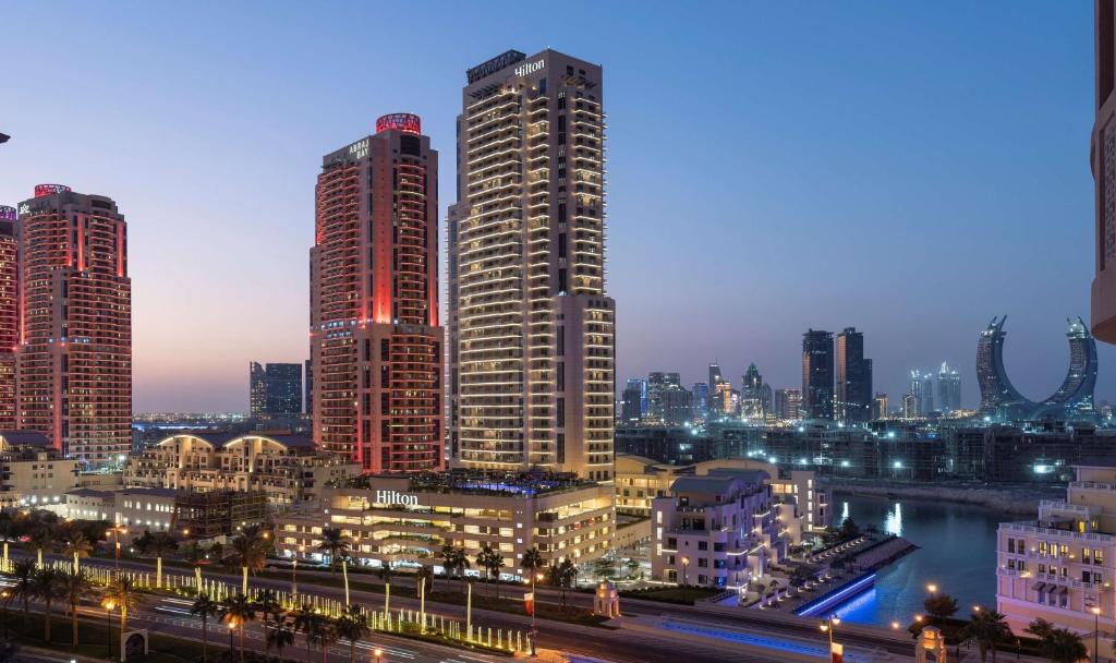 um horizonte da cidade à noite com edifícios altos em Hilton Doha The Pearl em Doha