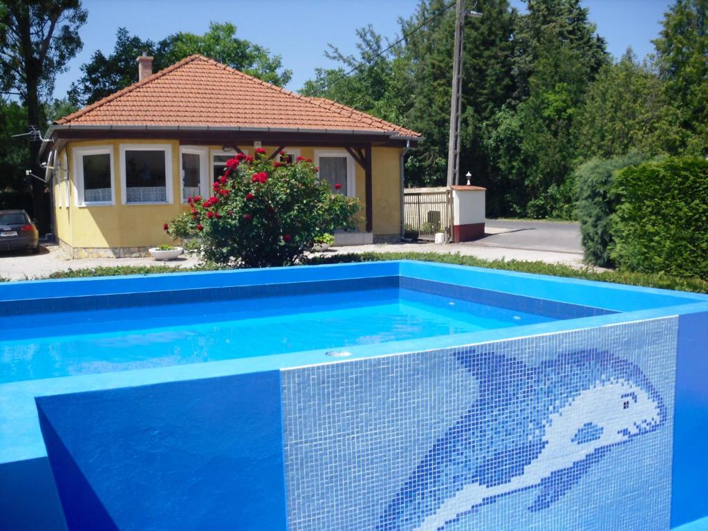 a blue swimming pool in front of a house at Tulipan Bungalow Camping Resort in Gyenesdiás