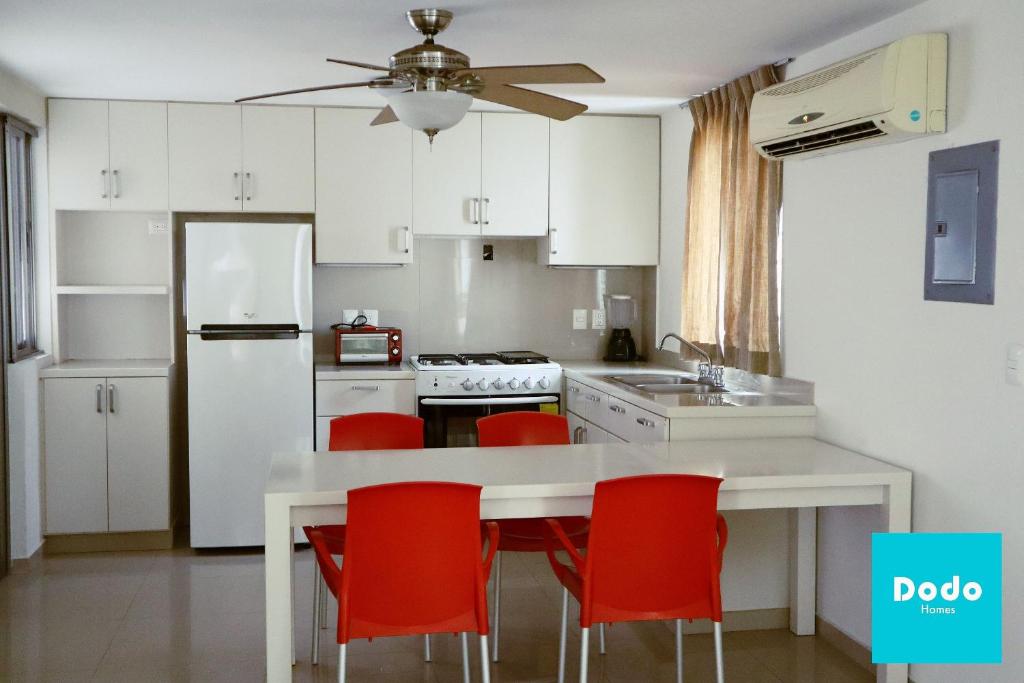 a kitchen with white cabinets and red chairs at Torre con alberca a 1 cuadra de la playa in Mazatlán