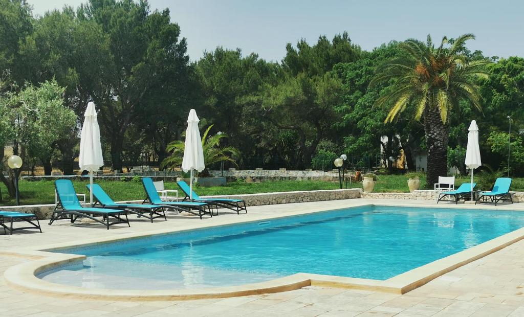 - une piscine avec des chaises et des parasols bleus dans l'établissement Residence Conchiglia San Giovanni, à Santa Cesarea Terme