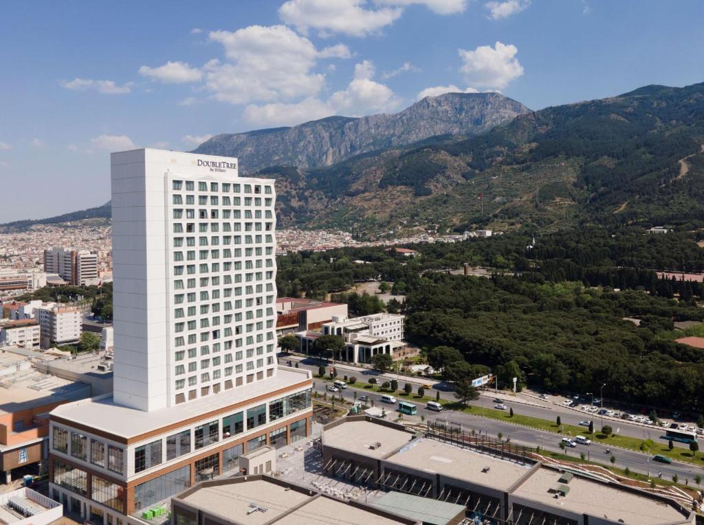 马尼萨DoubleTree by Hilton Manisa的一座高大的白色建筑,背景是群山