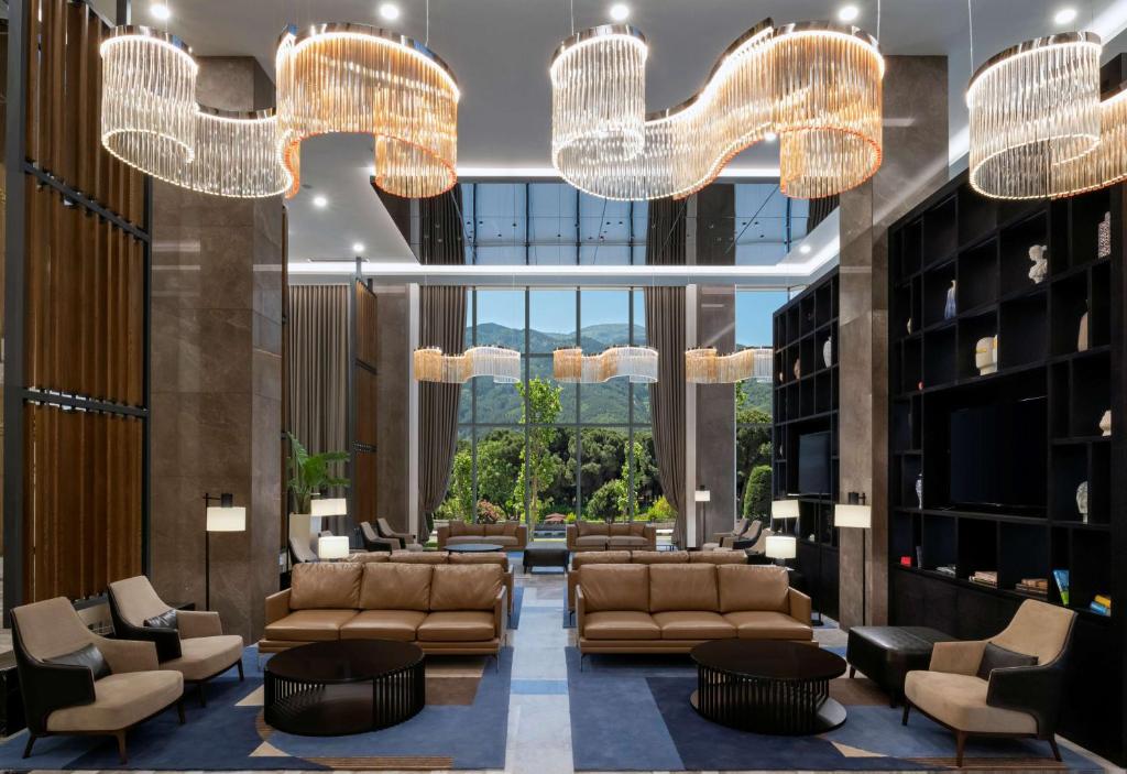 a lobby with couches and chairs and chandeliers at DoubleTree by Hilton Manisa in Manisa