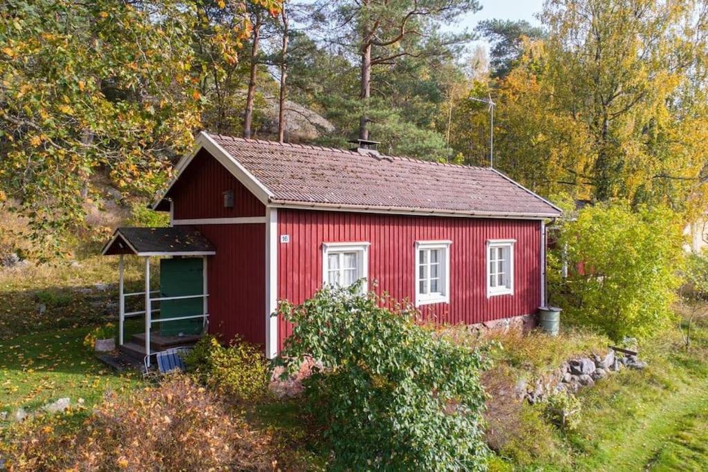 ein roter Schuppen an der Seite eines Hügels in der Unterkunft Little Guesthouse Cabin, Once Home to Lotta Svärd in Raasepori