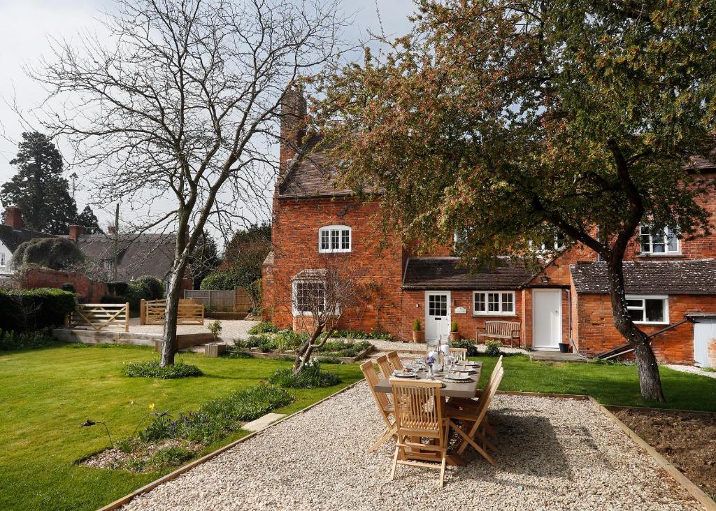 a garden with a table and chairs in front of a house at The Old School House in Evesham