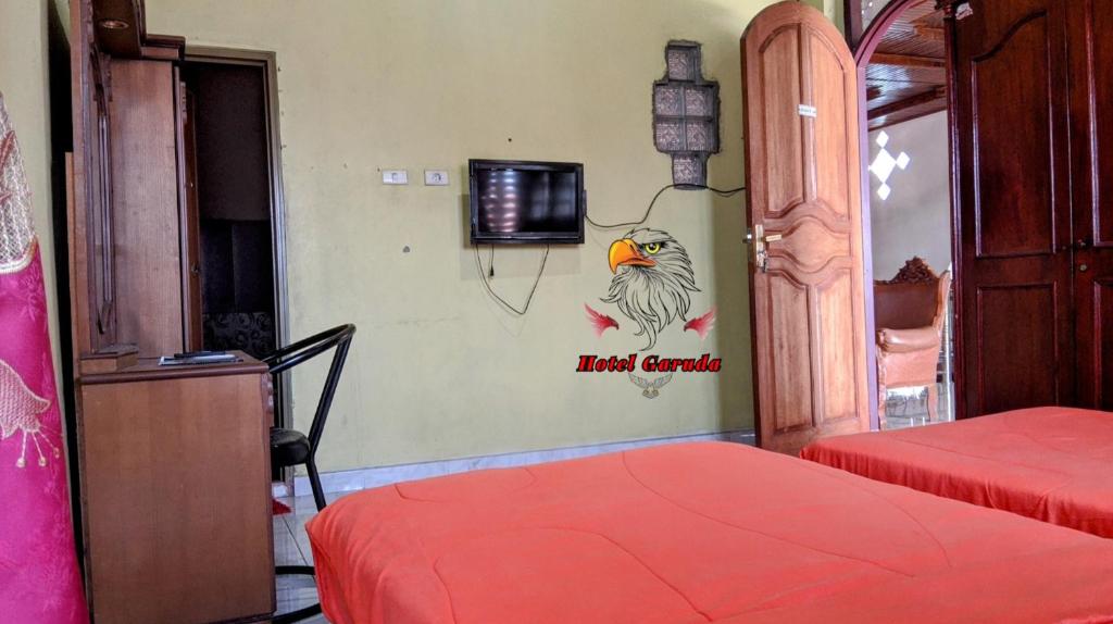 a room with two beds and a tv on the wall at Hotel Garuda in Rambah