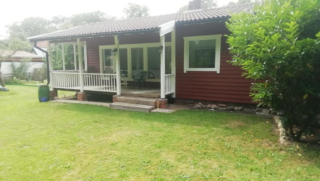 een klein huis met een veranda en een tuin bij Gästehaus an der Surheide in Ottersberg