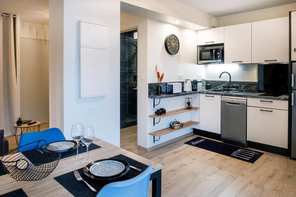 a kitchen with white cabinets and a table with a dining room at Appart. T 1 Bis, centre ville, entièrement rénové in Lourdes