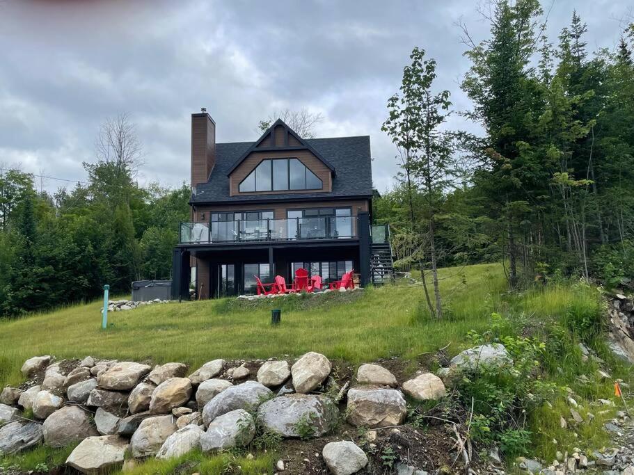 a large black house with red chairs on a hill at Au Coin Du Belvédère in Saint Come