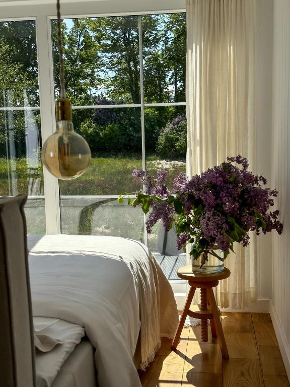 a bedroom with a bed and a vase of purple flowers at Ragnar Glamp Pitrags Lux in Pitragutsiyeme