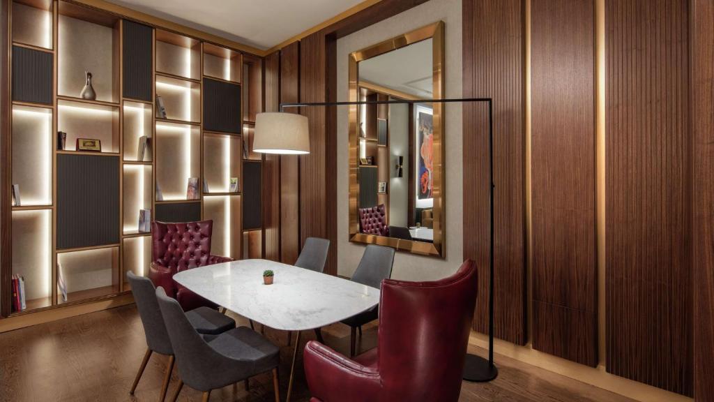 a dining room with a table and chairs and a mirror at Hilton Istanbul Maslak in Istanbul