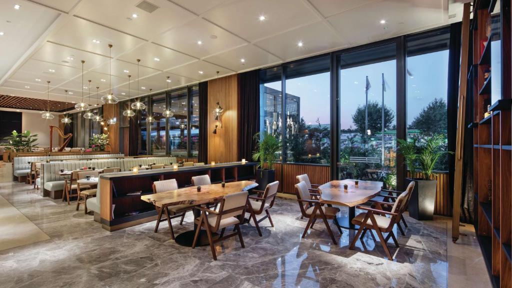 a restaurant with tables and chairs and a large window at Hilton Istanbul Maslak in Istanbul
