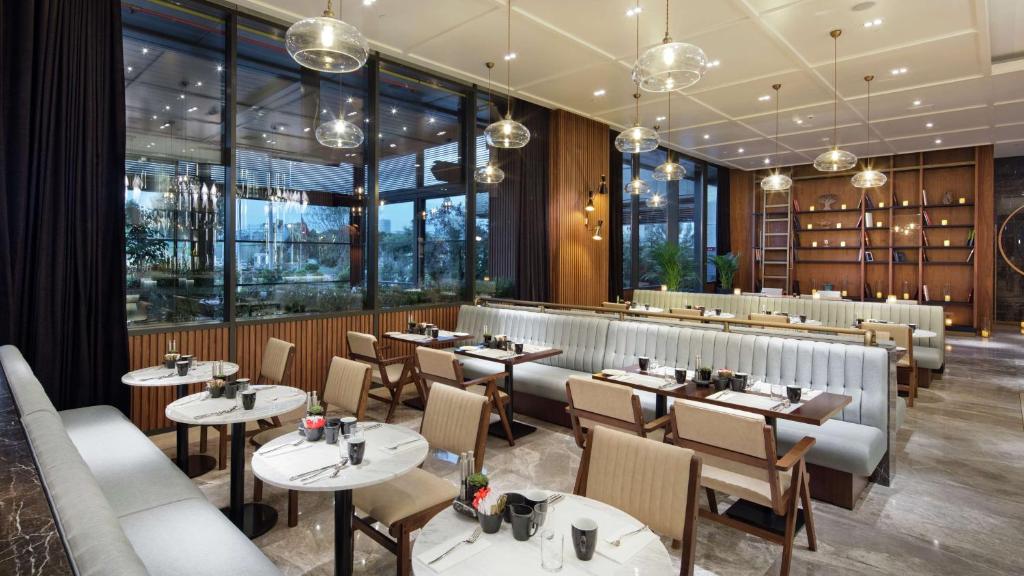 a restaurant with tables and chairs and windows at Hilton Istanbul Maslak in Istanbul