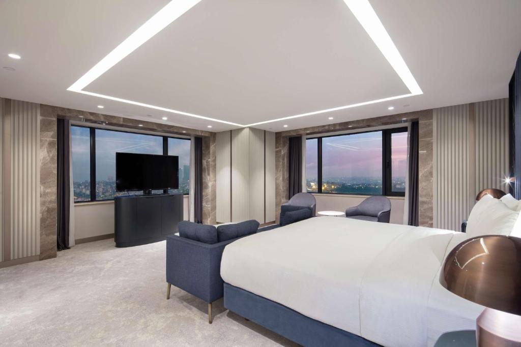 a bedroom with a large white bed and windows at Hilton Istanbul Maslak in Istanbul