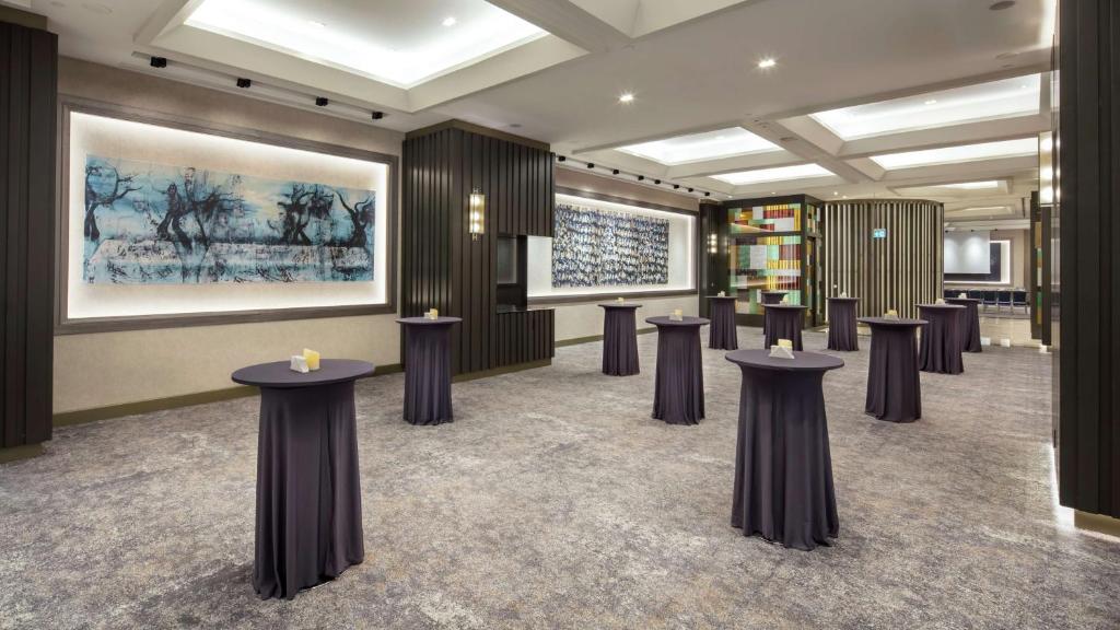 a row of tables in a room with a painting at Hilton Istanbul Maslak in Istanbul