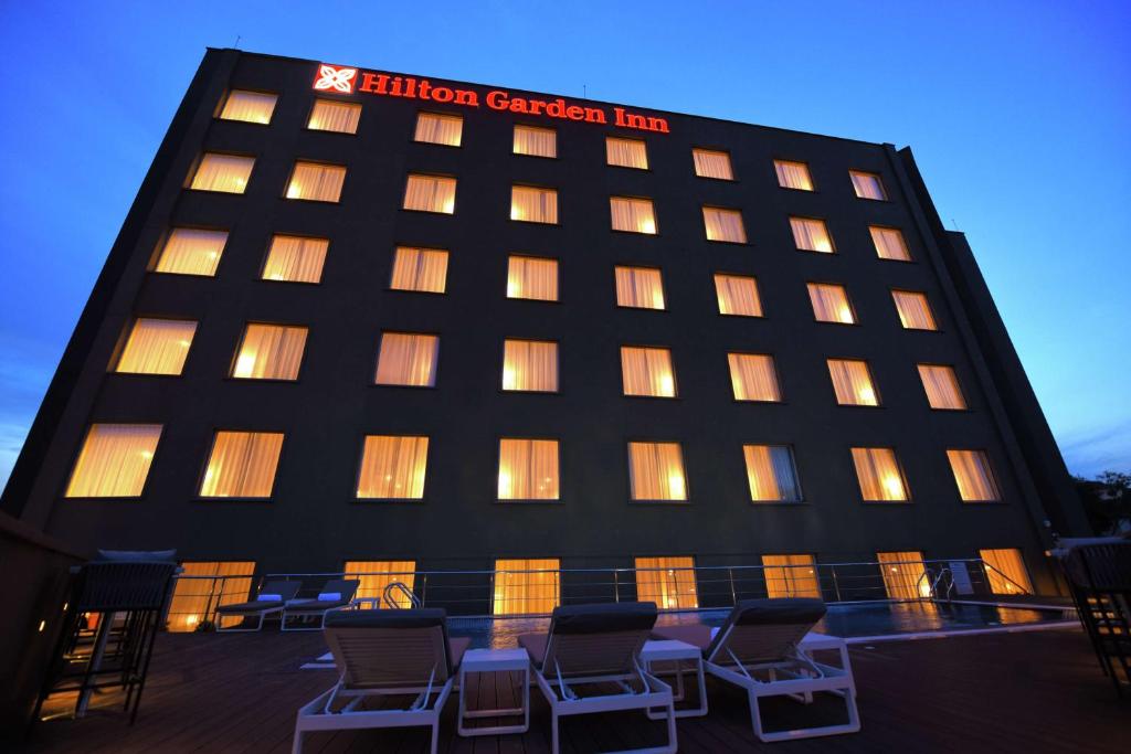 a hotel with chairs in front of a building at Hilton Garden Inn Kampala in Kampala