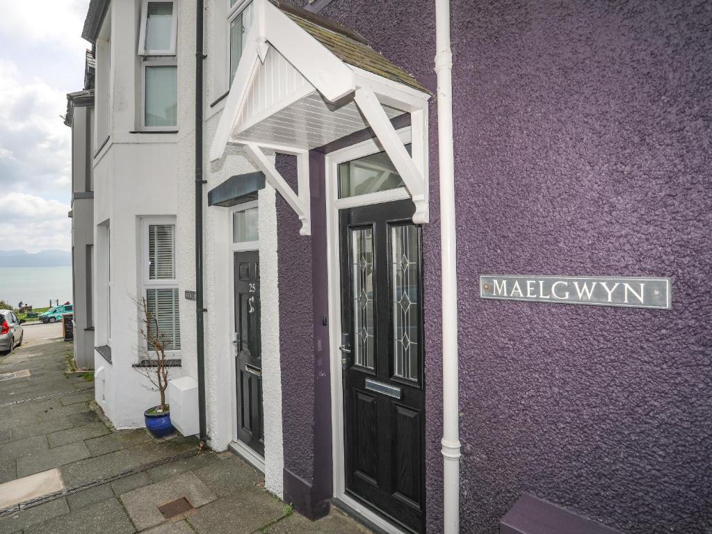 um edifício roxo e branco com uma porta preta em Maelgwyn em Criccieth