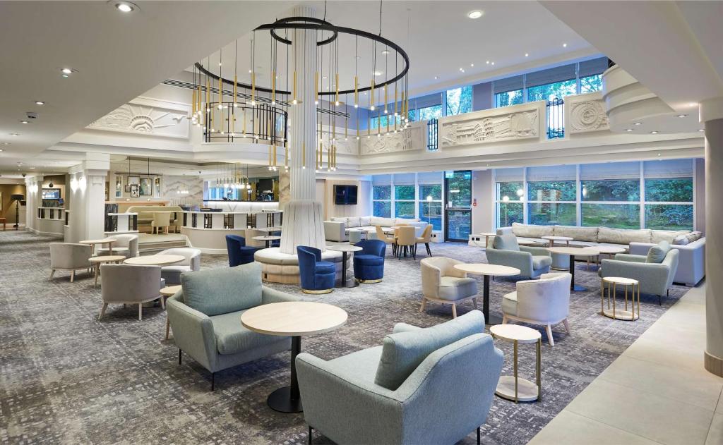 eine Lobby mit Tischen, Stühlen und einem Kronleuchter in der Unterkunft Hilton London Croydon in Croydon