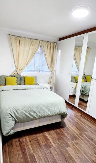 una camera con un letto e un grande specchio di Holiday Apartment a Abbey Wood