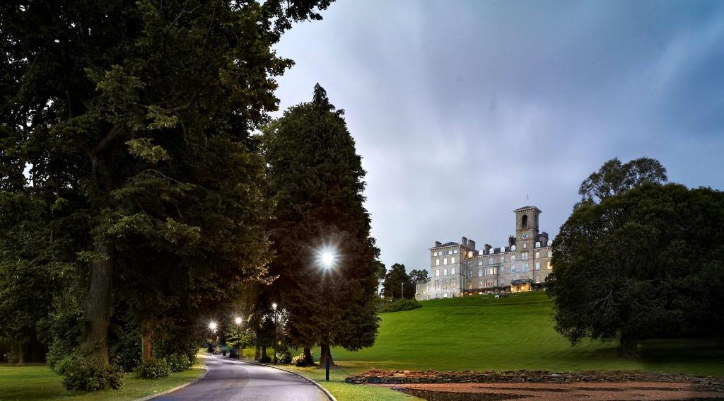 un bâtiment sur une colline avec une route devant dans l'établissement DoubleTree by Hilton Dunblane Hydro Hotel, à Dunblane