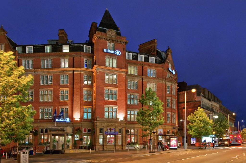 a large brick building on a city street at night at Hilton Nottingham Hotel in Nottingham