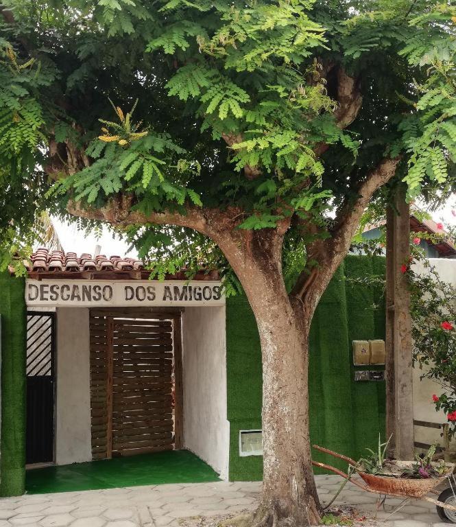 a tree in front of a green building with a sign at Casa Descanso dos Amigos in Prado
