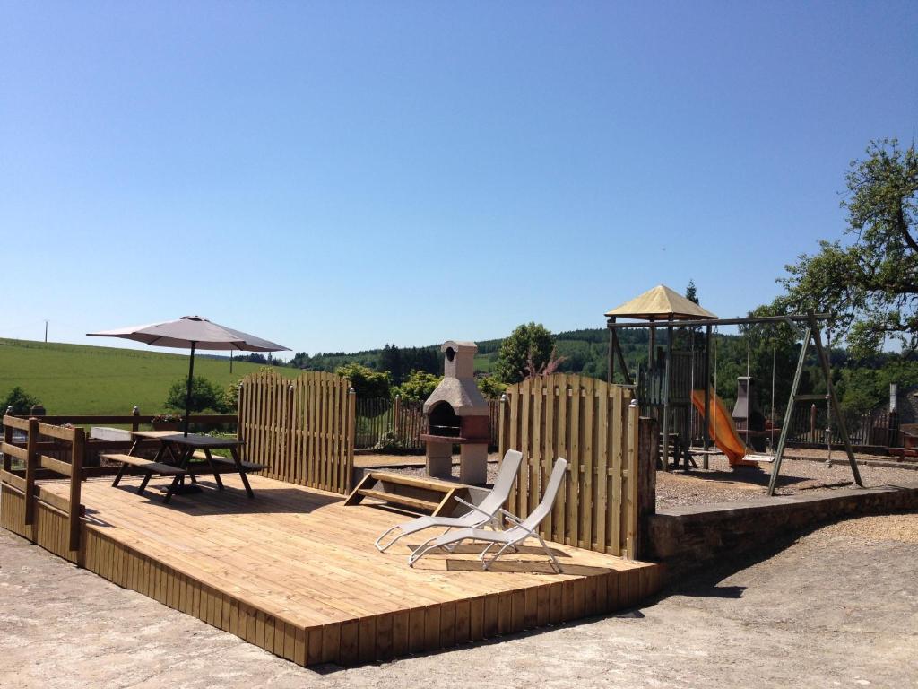 un parque infantil con 2 sillas y un columpio en Le Fenil Holiday Home, en Tenneville