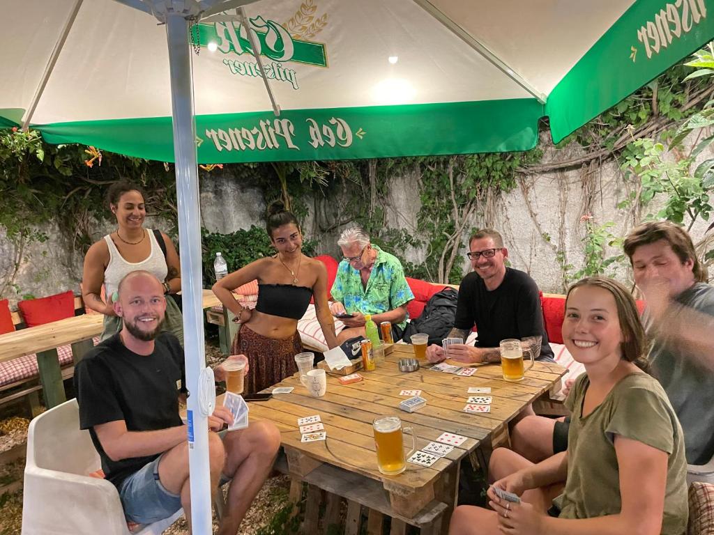 a group of people sitting at a table under an umbrella at Adriatic Hostel Vlora in Vlorë