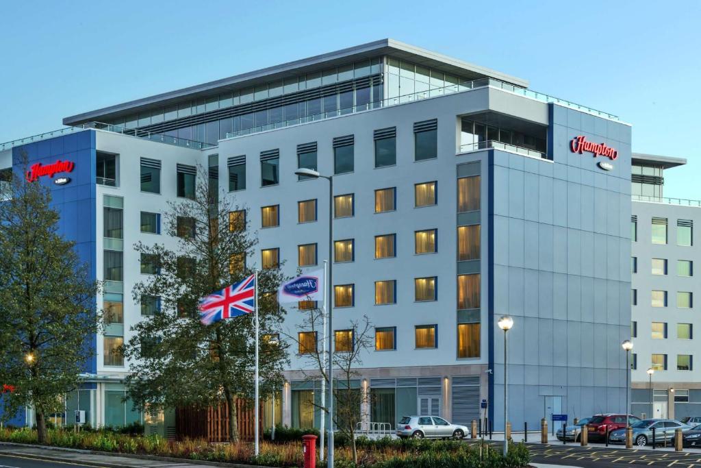 盧頓的住宿－漢普頓倫敦盧頓機場希爾頓酒店，大楼前方有uk旗的办公楼