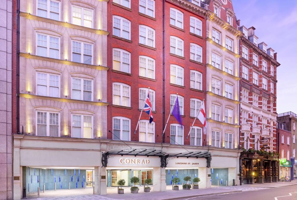 - un grand bâtiment rouge avec deux drapeaux dans l'établissement Conrad London St James, à Londres