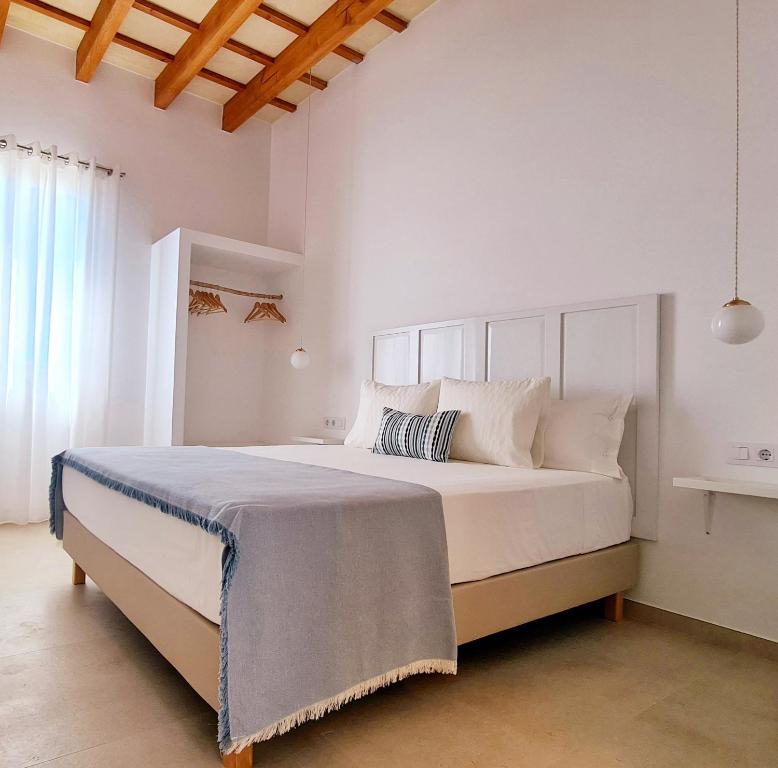a white bedroom with a large bed with white pillows at Waki Conscious Hotel in Ciutadella