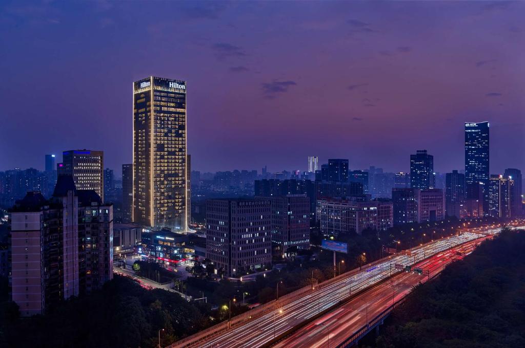 Una ciudad iluminada por la noche con tráfico en una autopista en Hilton Chongqing Liangjiang New Area en Chongqing