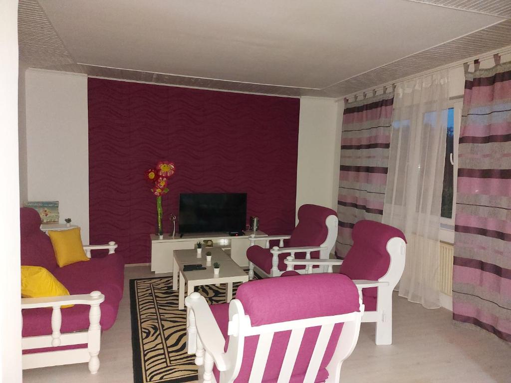 a living room with white chairs and a purple wall at Mona Apartments in Skopje