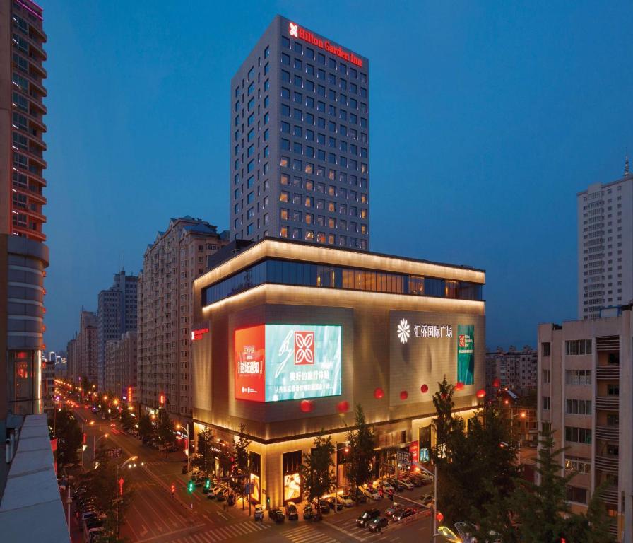 un gran edificio con un cartel en una ciudad en Hilton Garden Inn Dandong en Dandong