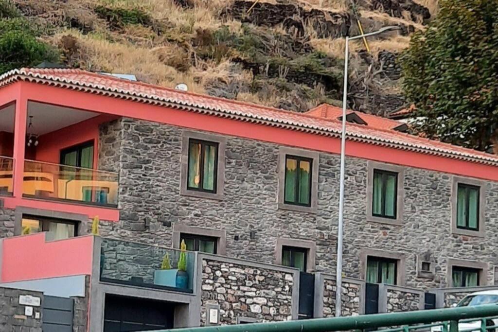 a stone house with a red roof and green windows at Chalé Esmeralda - Charming Studios in Calheta Beach in Calheta